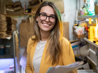 successful-small-business-owner-in-casual-wearing-yellow-cardigan-standing-in-her-store-looking-at_t20_G0BJEm